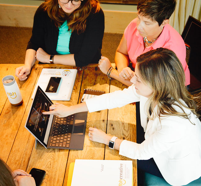 Team members around laptop discussing website strategy